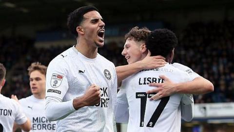 Kyrell Lisbie of Peterborough United and team-mates celebrate the opening goal scored during the League One match between Wycombe Wanderers and Peterborough United