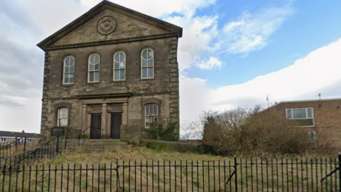 A Victorian Methodist church in Bingley. A stone building with two doors in the centre with a window on each side and four large window above