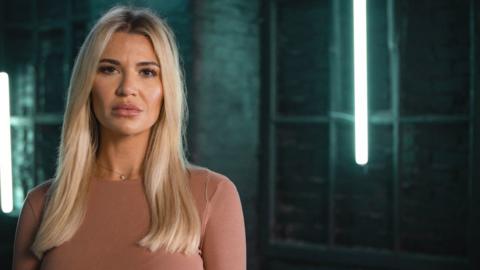 Christine McGuinness, a blonde woman wearing a pink top in front of a green background