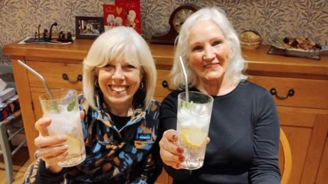 Lenise Blom and her sister Maria both smiling at the camera with a glass of gin and tonics in their hands.