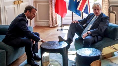 Boris Johnson places his right foot on a table at the Elysee Palace