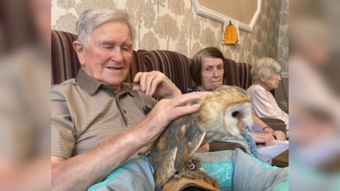 Care home residents sit with Bonzo, with one stroking her