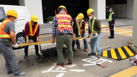 Construction workers cover with a metal plate parts of a painted slogan commemorating the 1989 Tiananmen Square crackdown, along the Swire Bridge at the University of Hong Kong (HKU) in Hong Kong