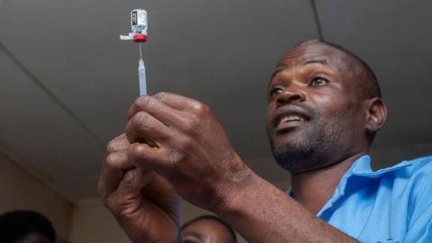 Man with syringe getting ready to adminster malaria vaccine