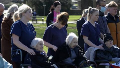 Care workers and their residents at a memorial in a park