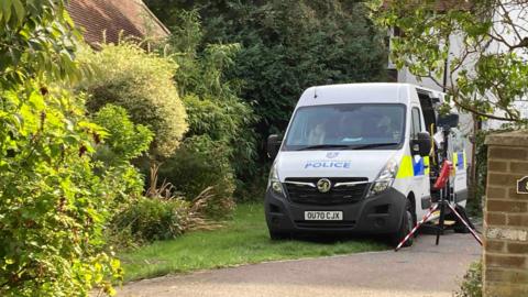 A police van parked rear-first in a driveway of a house