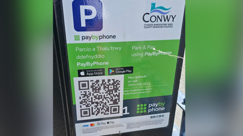 A Conwy council parking machine with a fake QR code in the bottom left corner