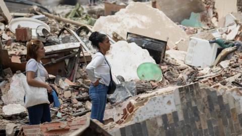 People look at the rubble of collapsed buildings in La Guaira, Venezuela