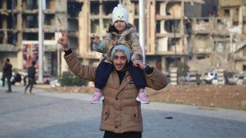 Man with girl on his shoulders celebrating Assad's removal