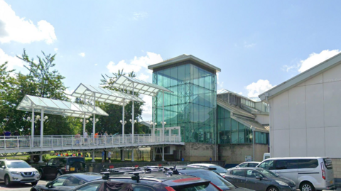 The entrance of Guildford Spectrum. A walkway leads up to the entrance, which is a rectangular green glass building.