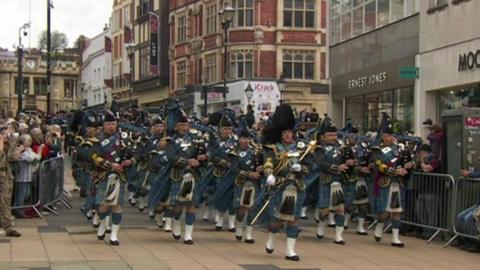 A marching band leads the way for a parade of RAF personnel in Lincoln.
