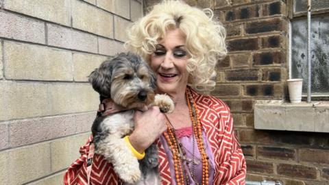 Paul O'Grady as Miss Hannigan holding dog