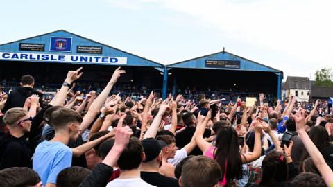 Carlisle United fans on the pitch at Brunton Park after the semi-final