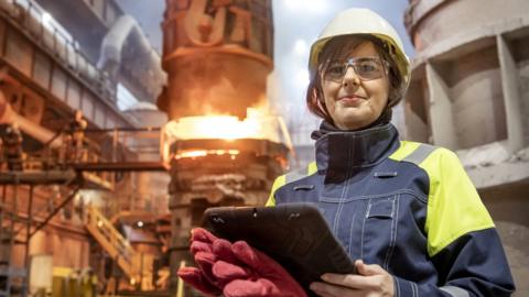 Portrait of female steelworker during steel pour in steelworks