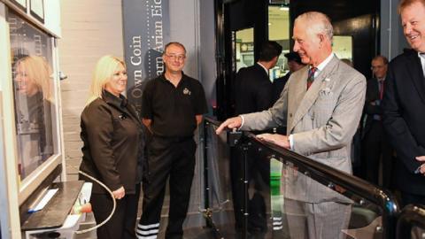 Prince Charles presses the button to strike the coin