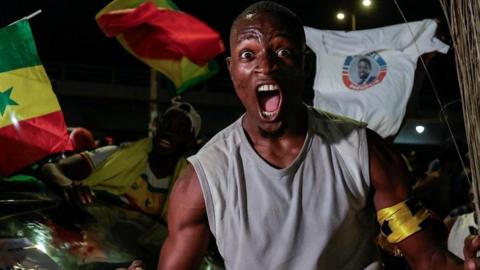 A Supporter of Senegalese presidential candidate Bassirou Diomaye Faye celebrates early results showing that Faye is leading initial presidential election tallies, in Dakar, Senegal, March 24, 2024