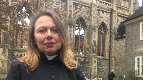 Reverend Kate Harrison outside the burnt-out church