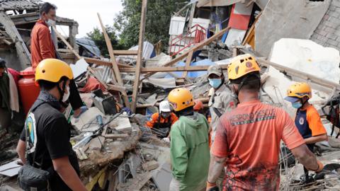 Rescuers search for victims at a collapsed house caused by a 5.6 magnitude earthquake, in Cianjur, Indonesia, 23 November 2022