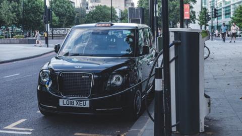 Black cab charging at side of the road