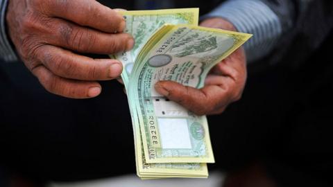 Man counting Nepalese money.