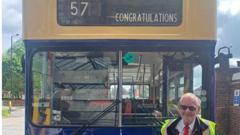 A driver in front of a bus