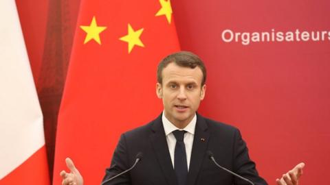 Emmanuel Macron speaks in front of Chinese and French flags