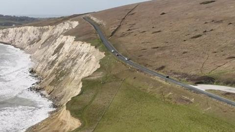 Cars pass close to the cliff edge on Military Road