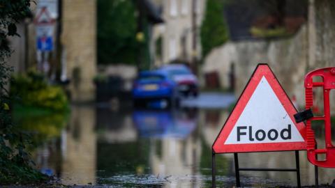 View of flood sign in front of a flooded street