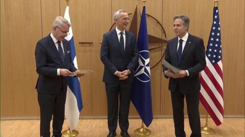 Three men, two hold documents.