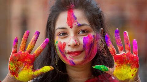 A woman shows off multi-coloured hands at the Holi festival