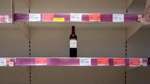 Bottle of wine on an empty supermarket shelf