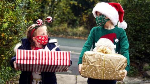 Children with Christmas presents and face coverings