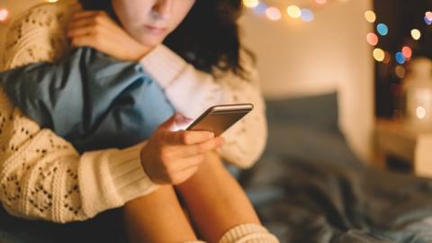 Generic photo of girl using a phone on her bed