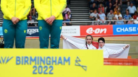 England's Sophie Unwin and Georgia Holt hold up the England flag behind the podium