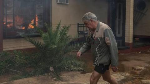 A man walks past a burning house in Coligny that was reportedly set on fire by protesters during clashes that erupted after a court bailed two men accused of killing a boy on May 8, 2017