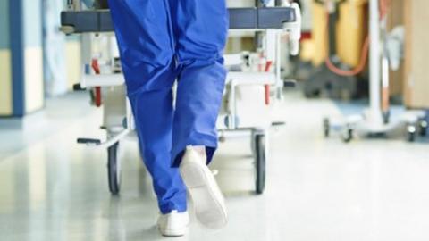 Legs of medic running with trolley along hospital corridor