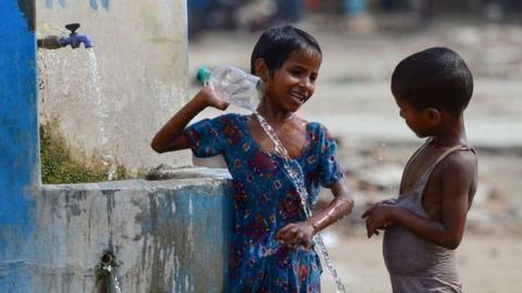 Indian children take a bath at a roadside tap during a hot summer afternoon in Allahabad on June 2, 2019