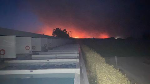 A red glow seen in the sky, hotel in foreground.