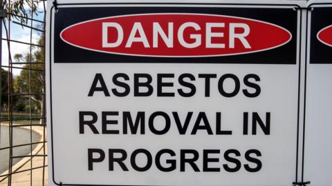 A sign warns of asbestos removal dangers