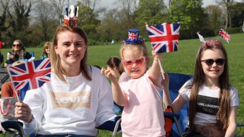Two young girls and their mum waves flags in Sunderland