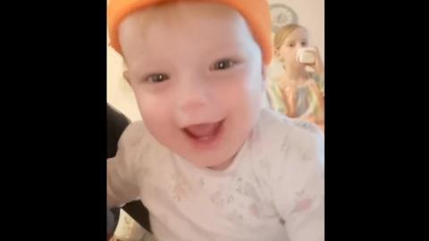 Baby Delilah, smiling with an orange wool hat