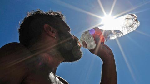 A man drinks water on Copacabana Beach in Rio de Janeiro, Brazil, 19 September 2023, during a heatwave