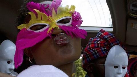 People wearing masks pose as they sit in a vehicle during the first Ugandan gay pride rally since the overturning of a tough anti-homosexuality law, which authorities have appealed, in Entebbe, on August 9, 2014