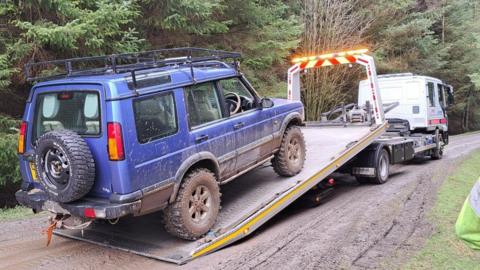 A blue 4x4 vehicle being loaded on to the back of a lorry