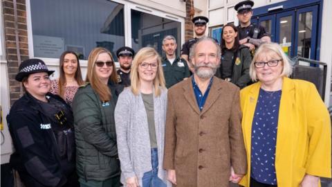 Andre Dickinson (middle) with his wife, daughter and emergency service personnel who helped save his life