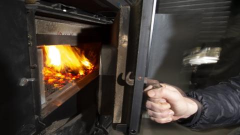 A person opening a boiler door