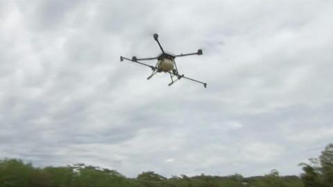 A drone is seen against the sky in this photo, above a field