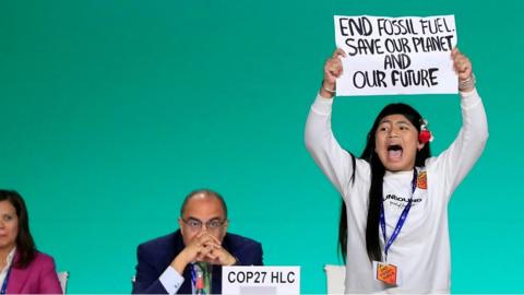 Licypriya Kangujam shouting and holding up a sign at COP28