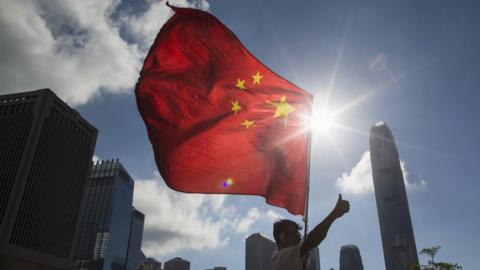 Chinese flag in front of Hong Kong skyline