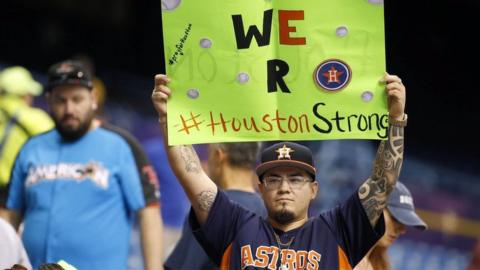 Houston Astros fan holds up a sign for those impacted with Hurricane Harvey